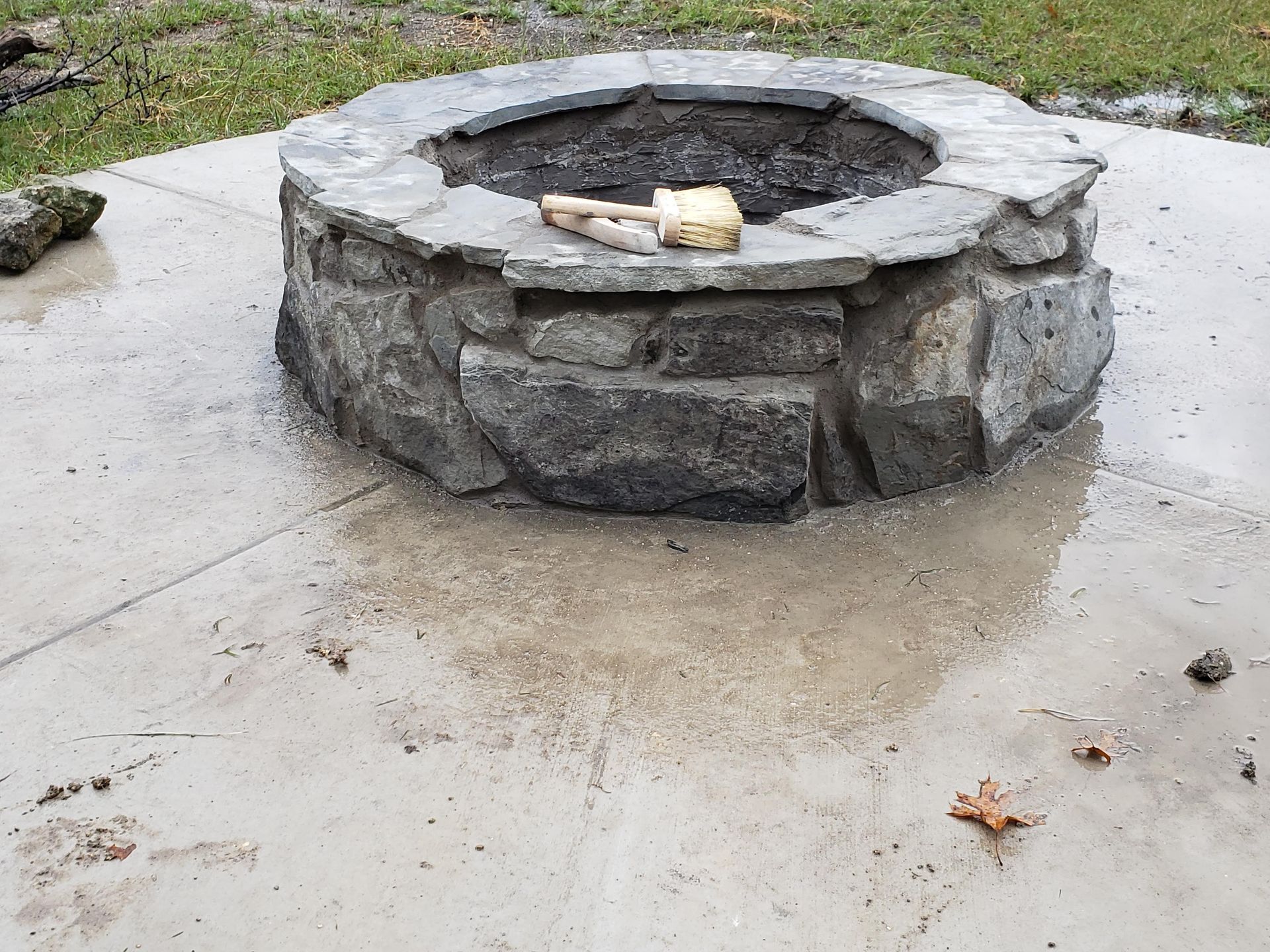 Stone fire pit on a concrete surface, with a log inside.