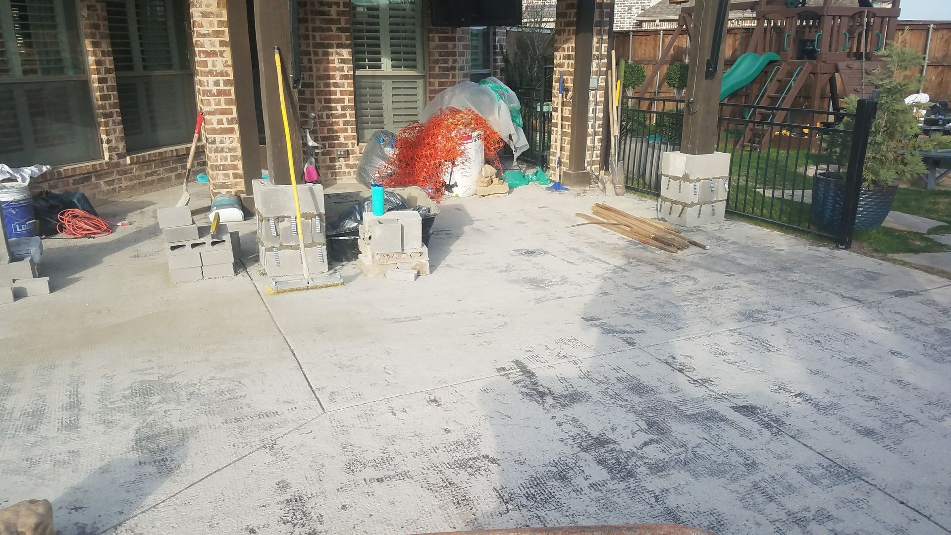 Patio under construction with concrete, cinder blocks, and construction materials.