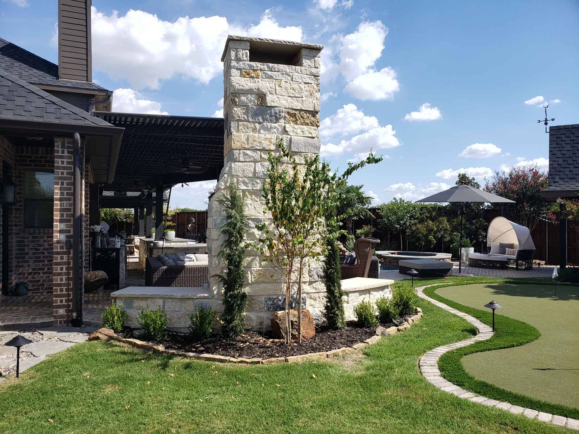 A Backyard with a Stone Fireplace- Tulsa, OK - Outdoor Orchestrators