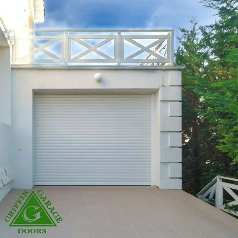 A white garage with a green triangle that says griffin garage doors