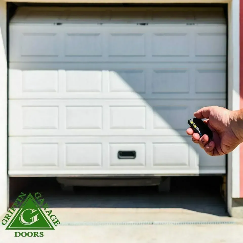 A person is holding a remote control in front of a garage door