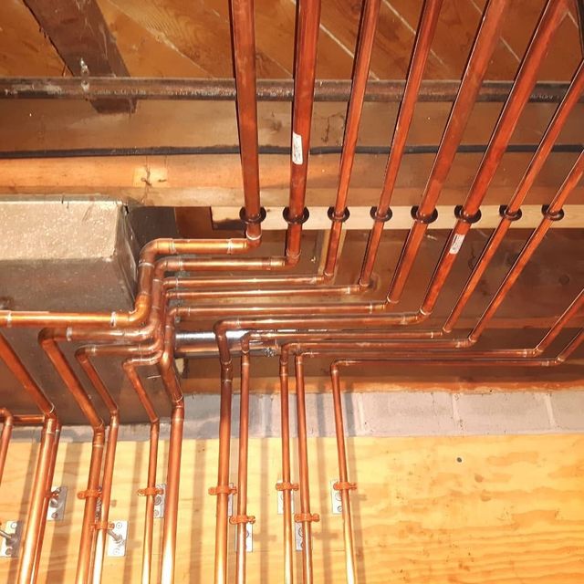 Concrete basement with exposed wooden beams, a staircase, and a low concrete ledge.
