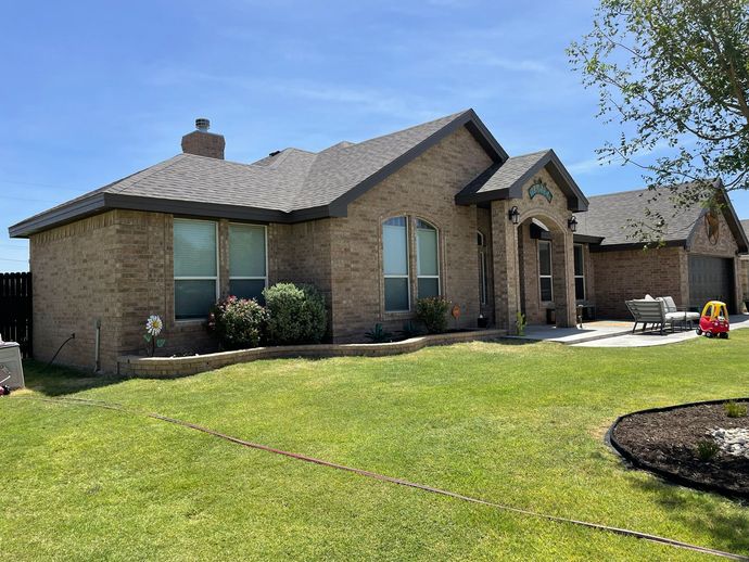 A large brick house with a lush green lawn in front of it.