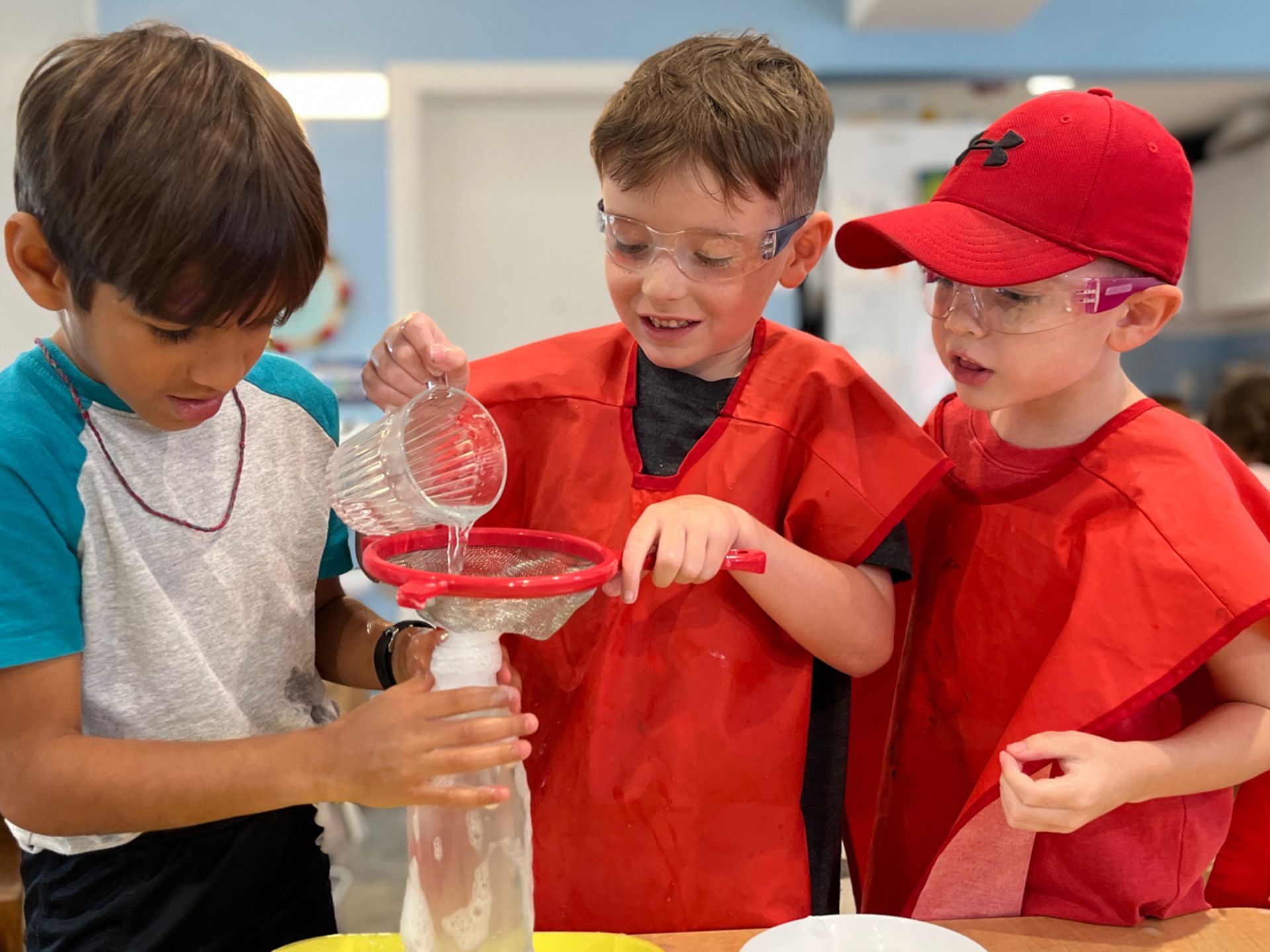 Montessori children pouring water into a container