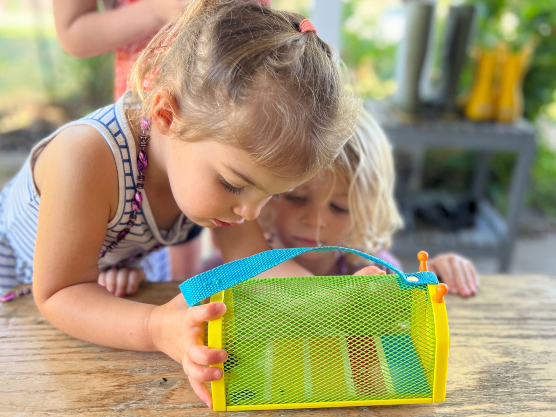Two Montessori little girls are playing with a yellow and green toy
