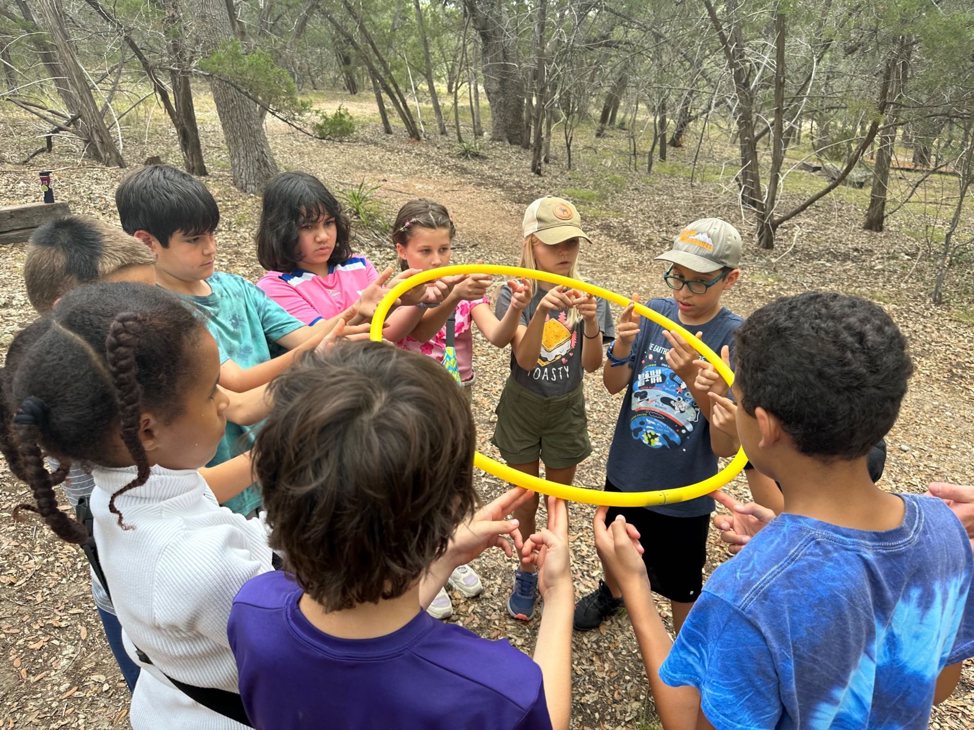 A group of Montessori children are holding a yellow hoop in a circle
