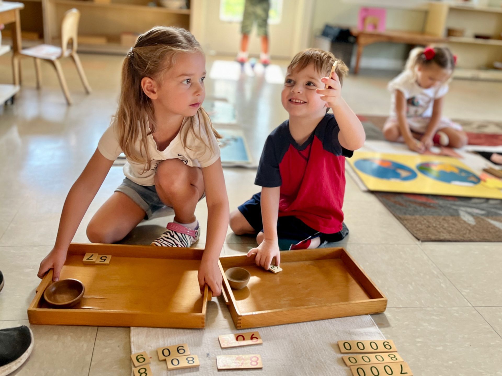 A  boy and a girl are playing with numbers on a tray