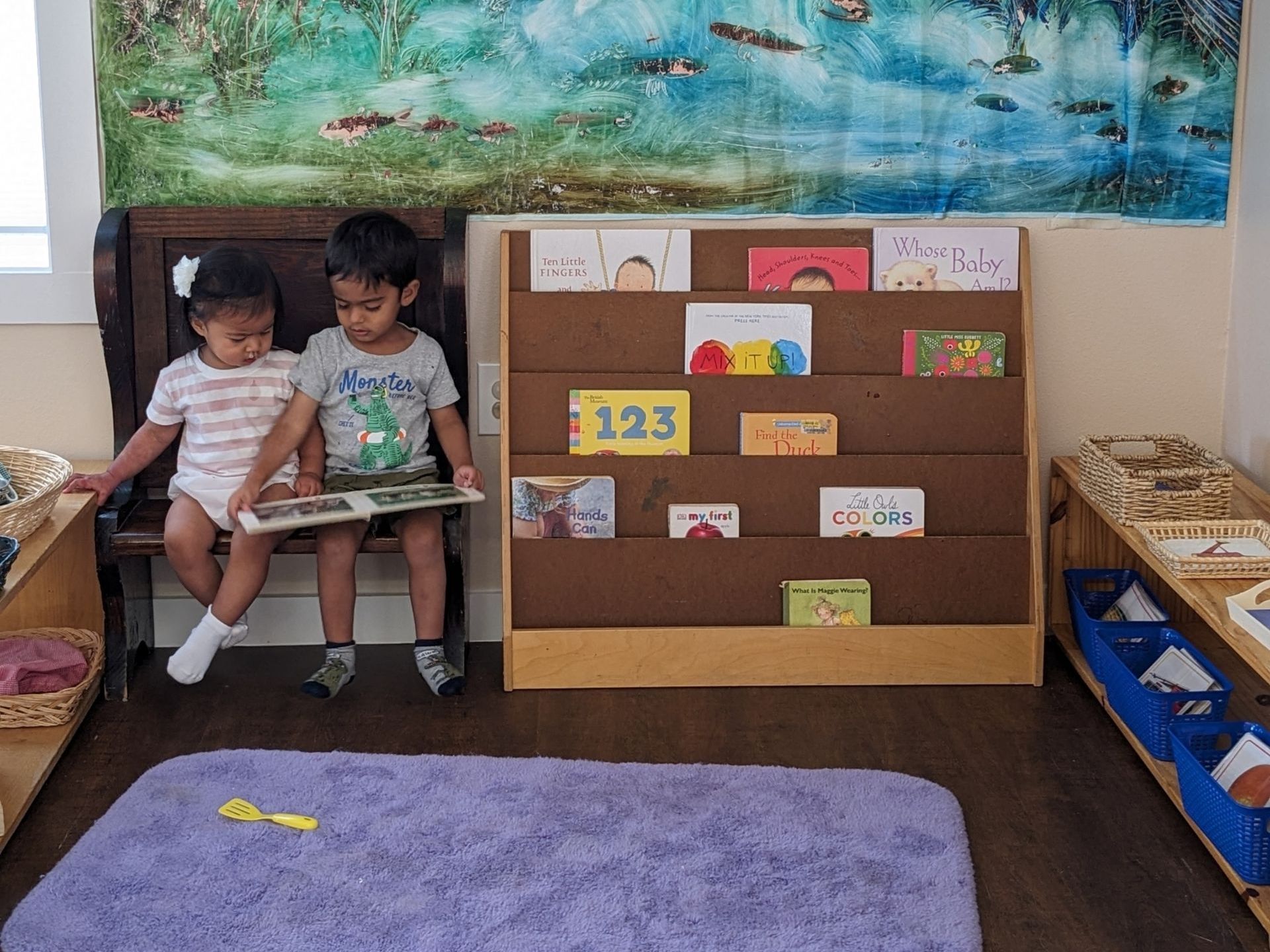 Montessori children sitting next to a bookshelf
