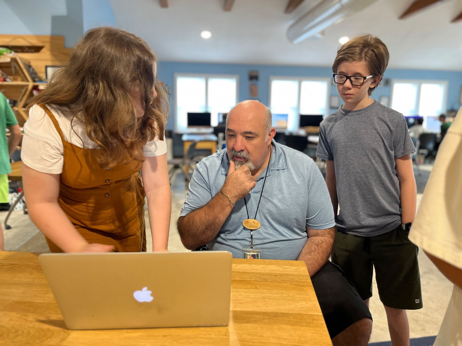 Montessori guide with students looking at a laptop