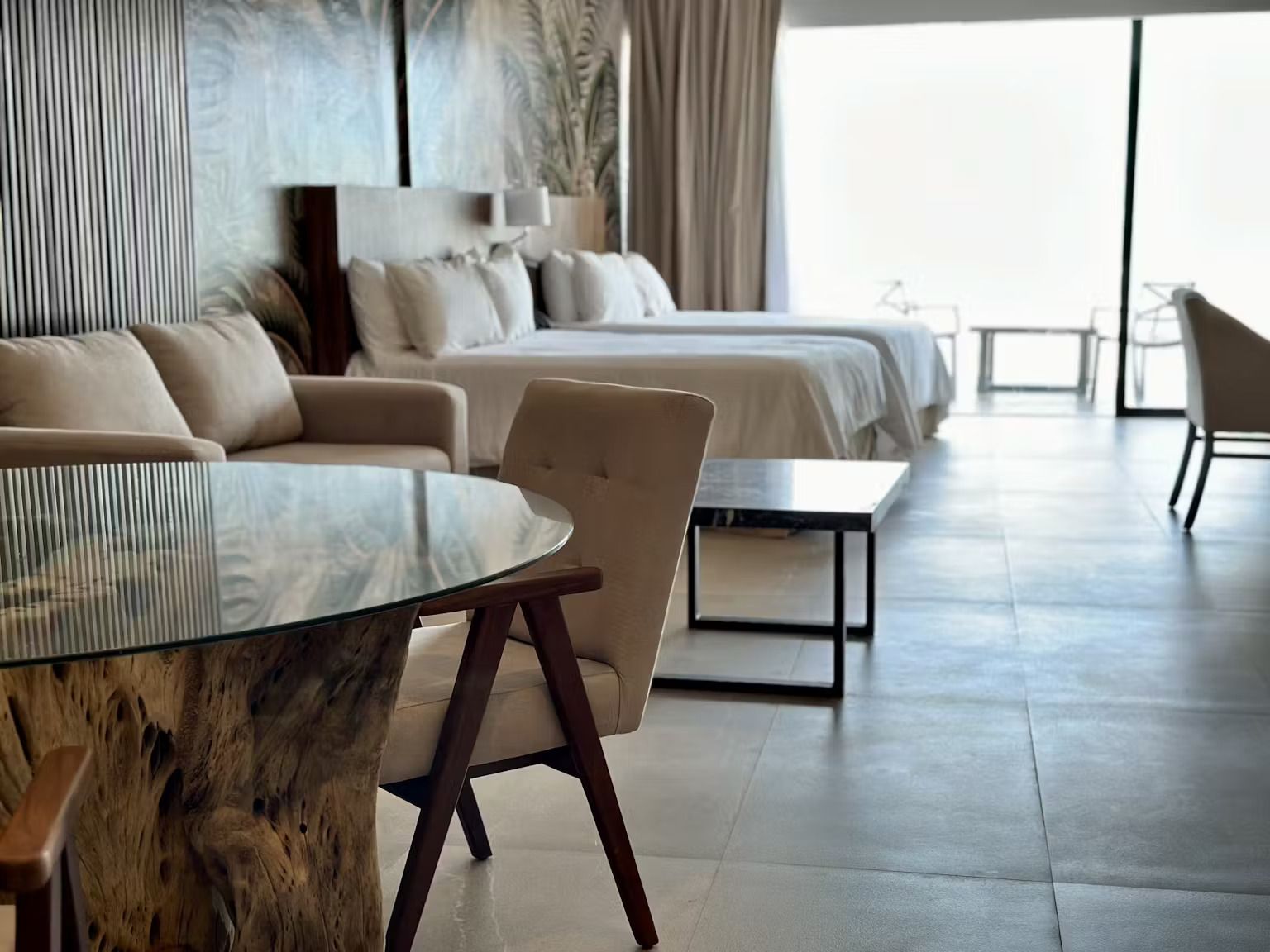 A hotel room with two beds , a table , chairs and a couch.