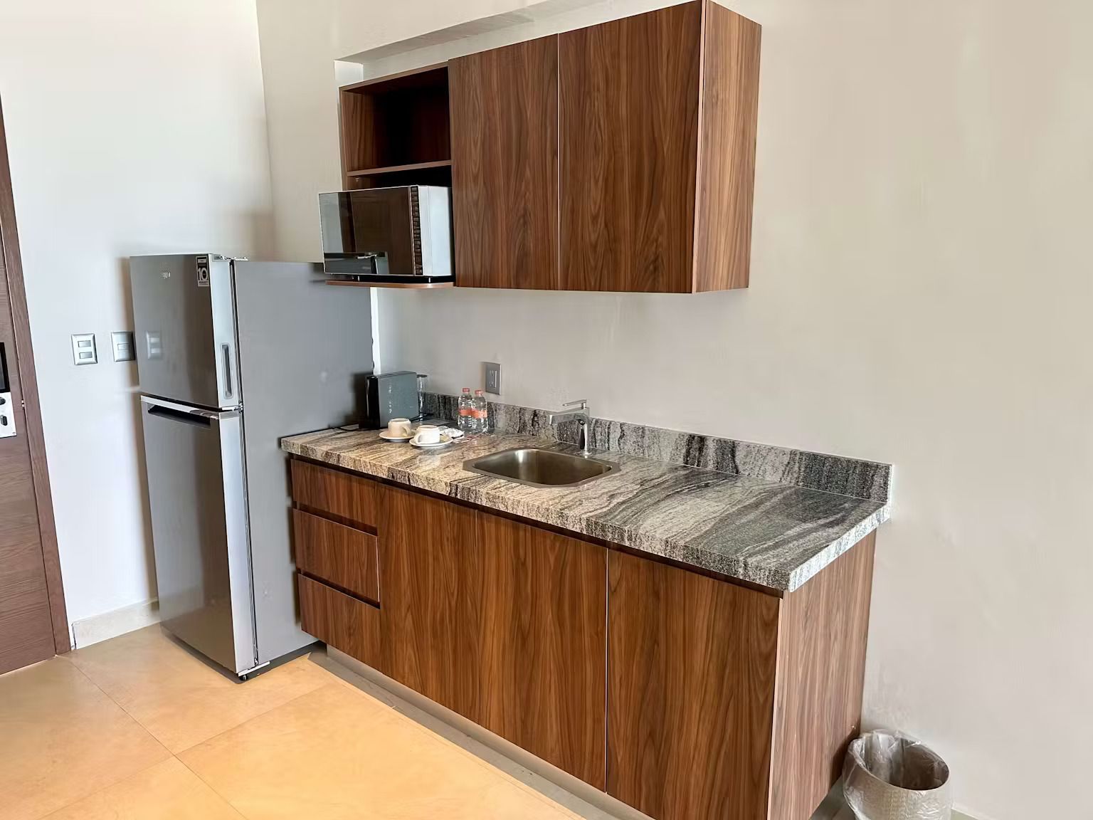 A kitchen with a refrigerator , sink , and cabinets.