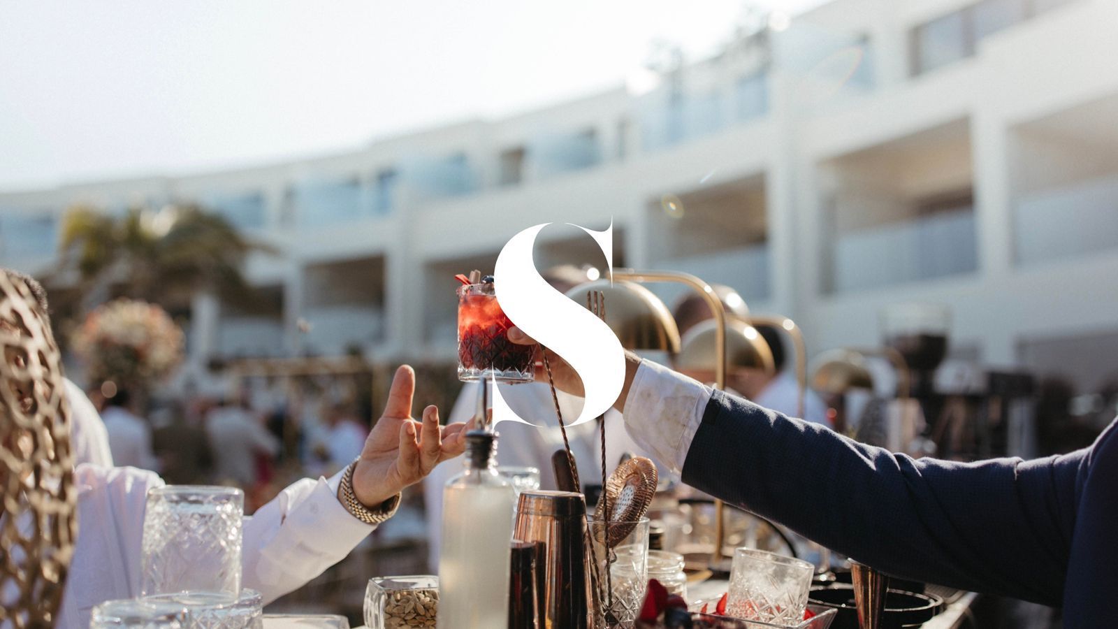 A man is pouring a drink into a glass at a party.