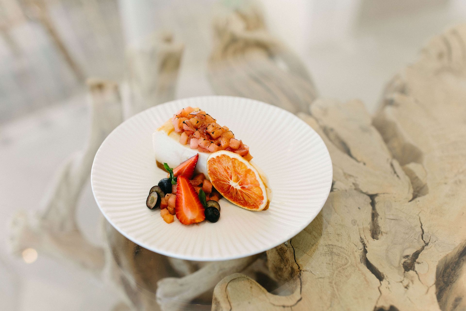 A white plate topped with a piece of cake and fruit on a table.