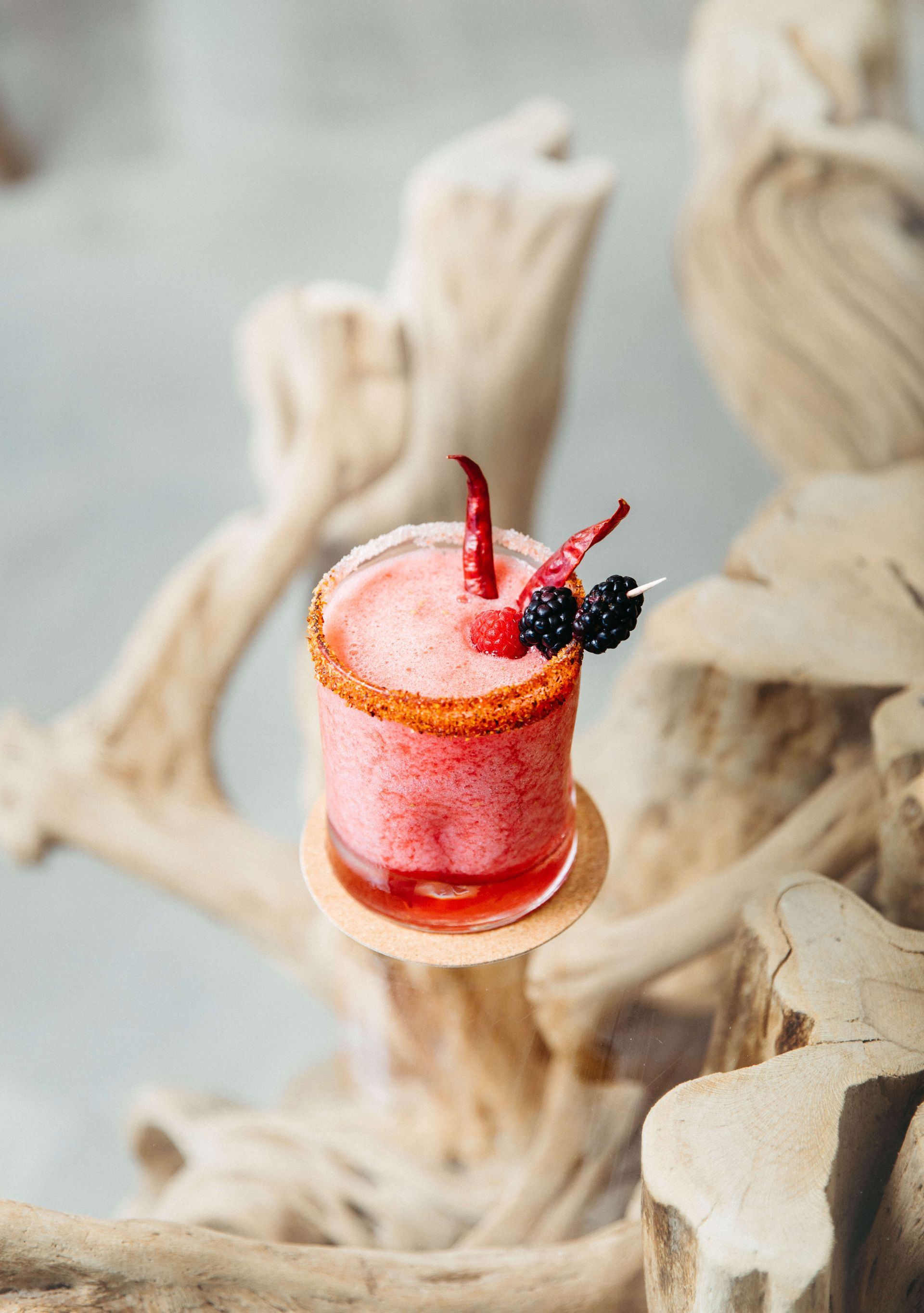 A close up of a drink in a glass on a wooden table.