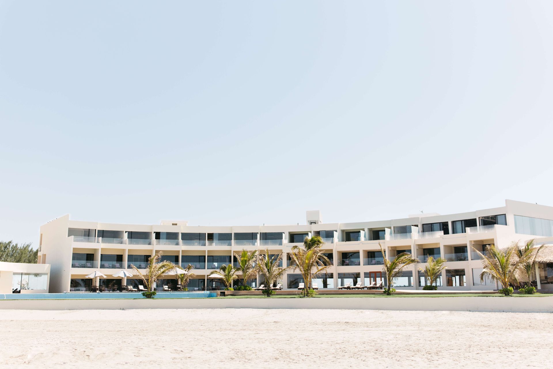 A large white building is sitting on top of a sandy beach.