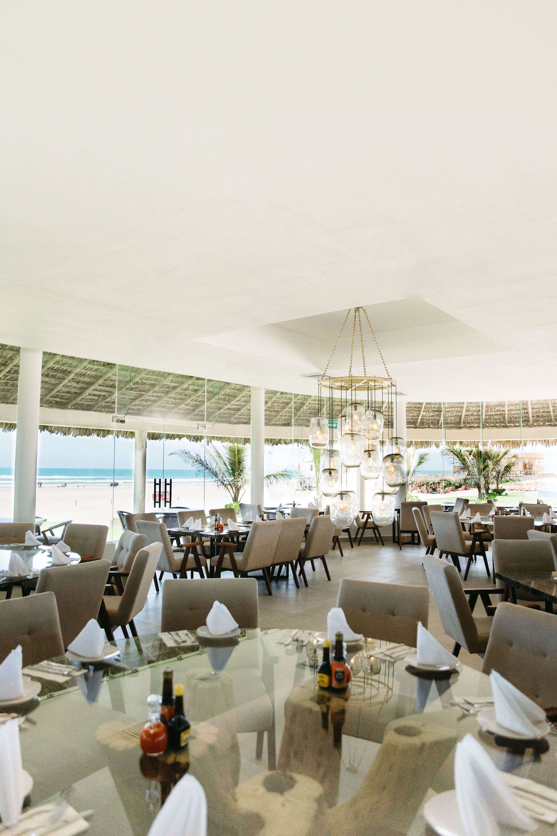 A large dining room with tables and chairs and a view of the ocean.