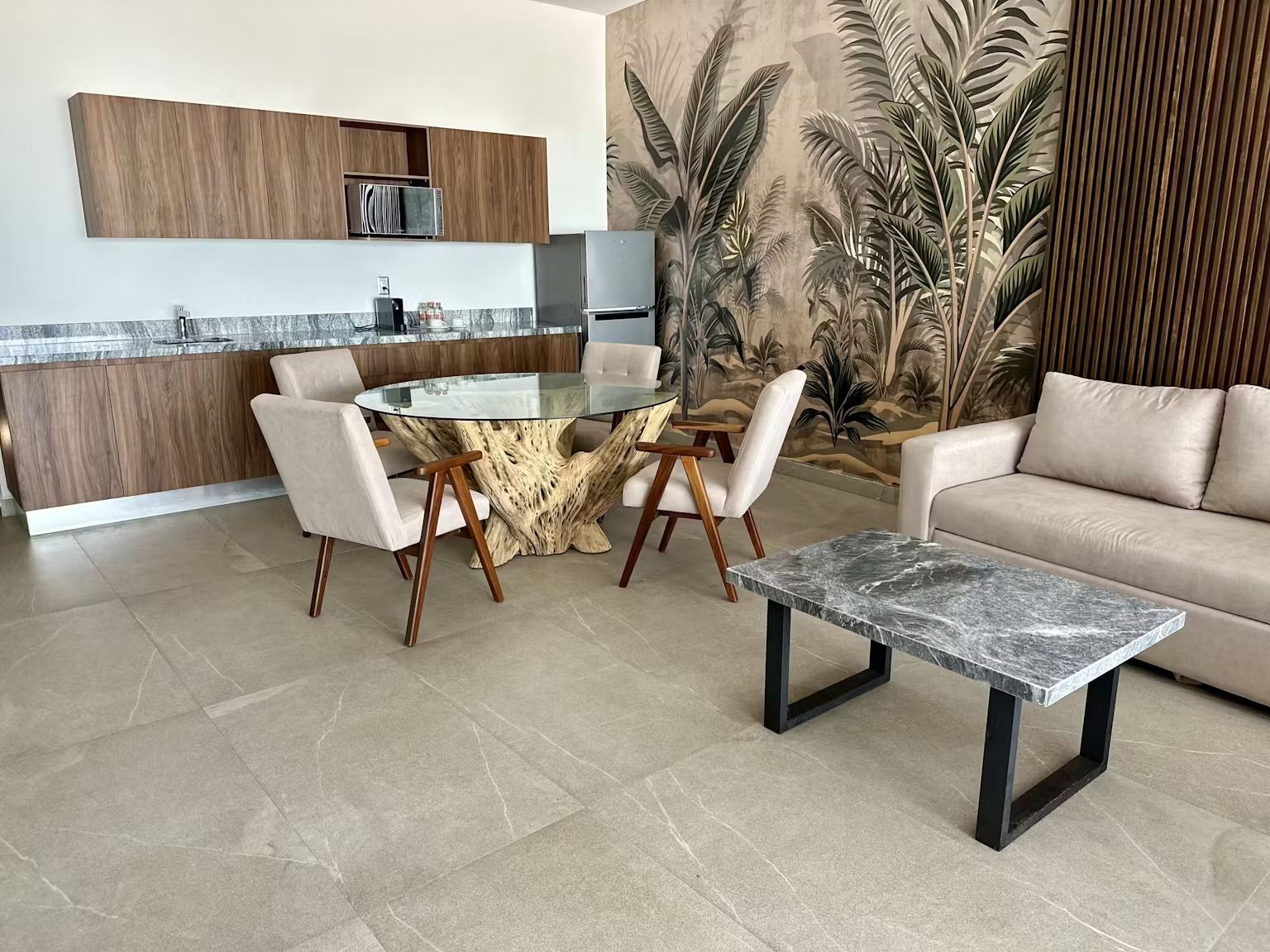 A living room with a couch , table , chairs and a kitchen.