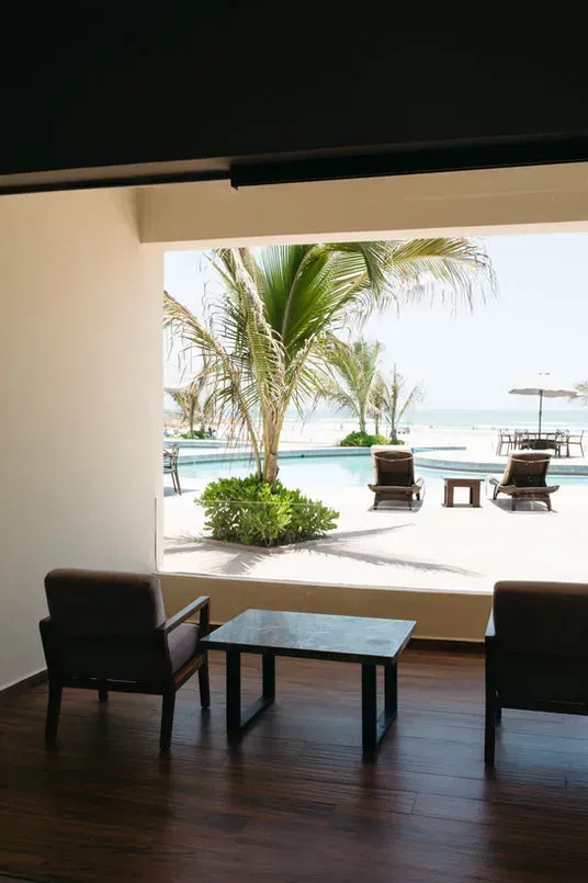 Una habitación con dos sillas y una mesa con vista a una piscina.