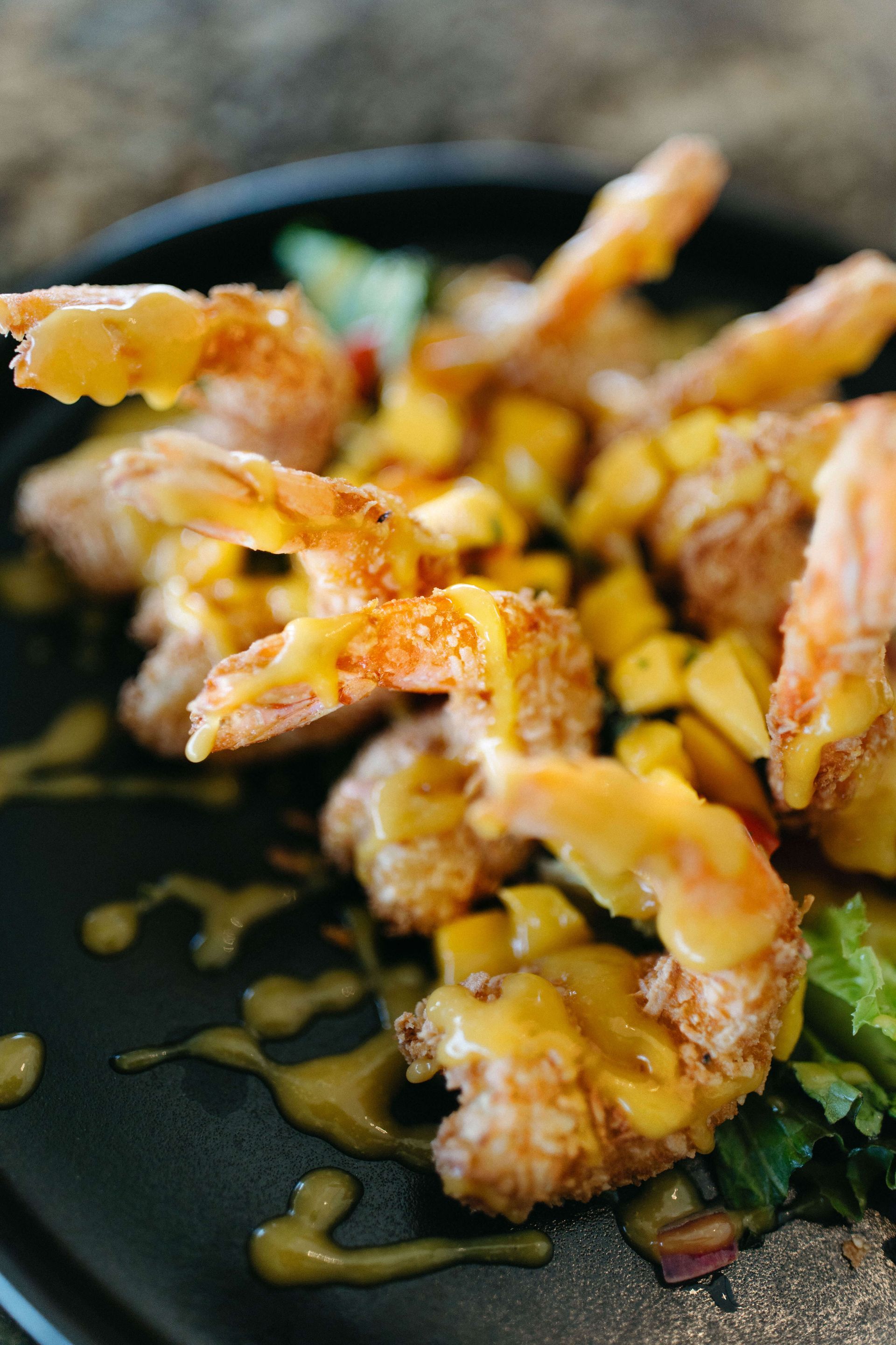 A close up of a plate of fried shrimp with sauce on a table.