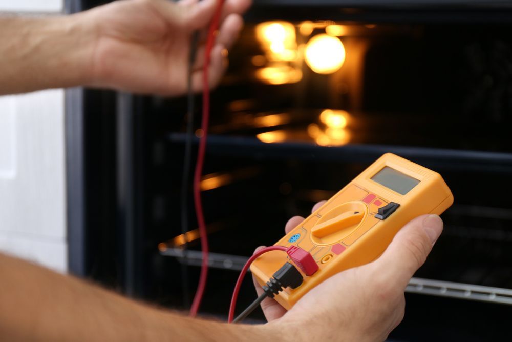 Hands Testing an Oven Light With a Multimeter — Big Electrics in Redlynch, QLD