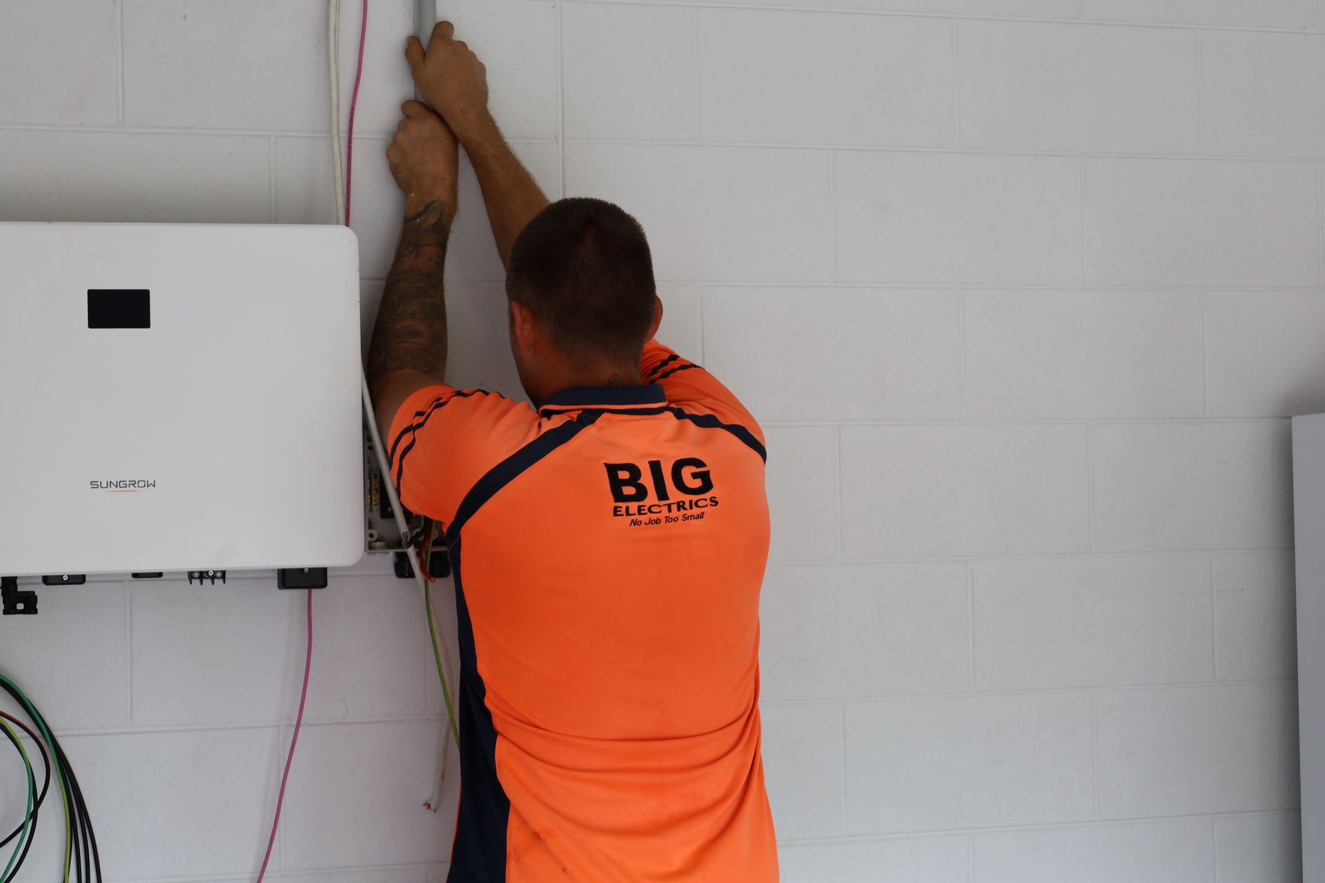 Worker Installing Solar Panels on a Rooftop Under a Blue Sky — Big Electrics in Redlynch, QLD