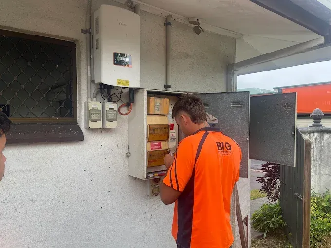 Man in Gray Gloves Repairing an Ac Unit Outdoors on a Sunny Day — Big Electrics in Redlynch, QLD