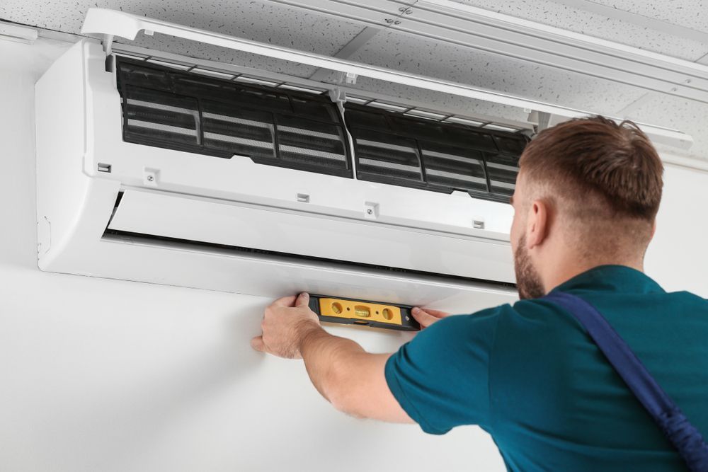 Man Using a Level to Install an Air Conditioner — CQ Refrigeration Air-Conditioning & Electrical Pty Ltd in Lammermoor, QLD