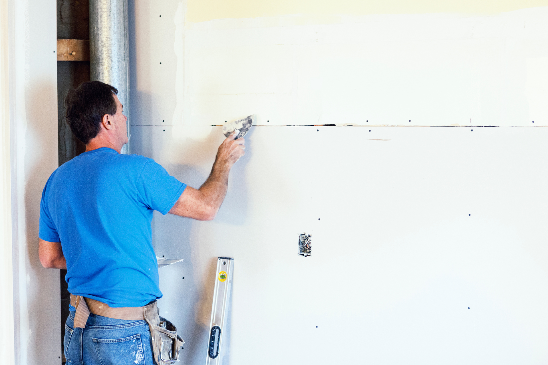 A man is measuring a wall with a tape measure.