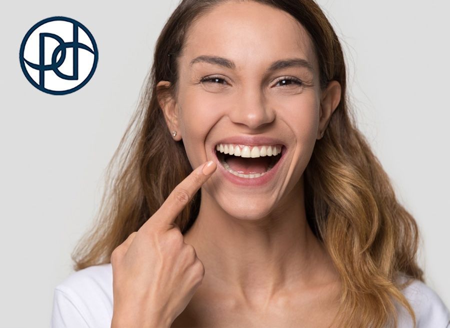 Woman smiling widely, pointing at her teeth.