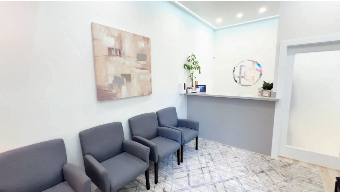 Dentist's gloved hands holding a dental tool with a buffing pad near a denture, on a blue surface.