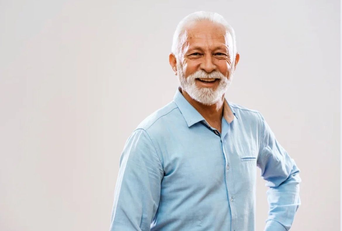 Close-up of a person's open mouth, showing a full set of white teeth. The person has stubble.