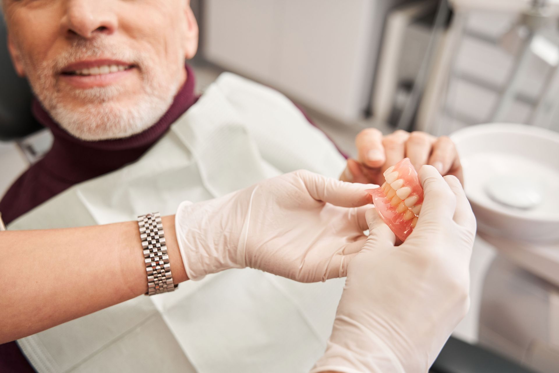 Dentist holding dentures, showing a patient in a dental office.