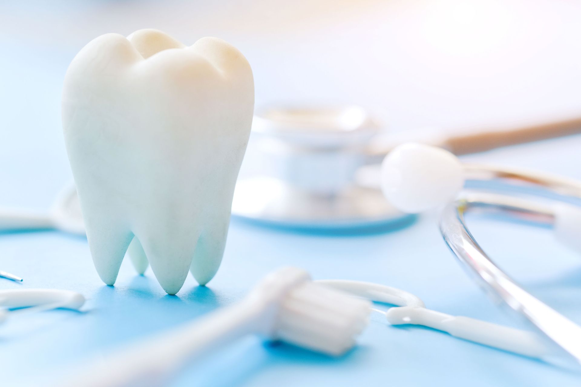 White model tooth with dental tools on a blue surface.