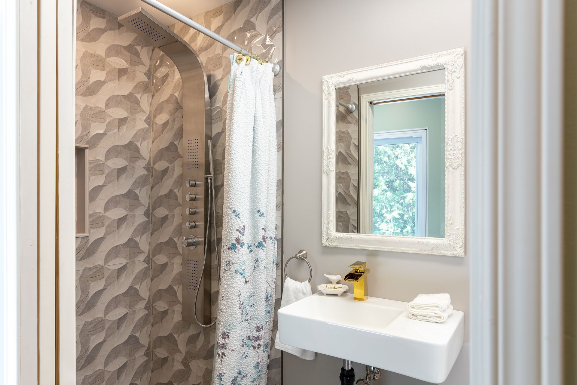 Small modern bathroom with a shower, floating sink, and framed mirror.
