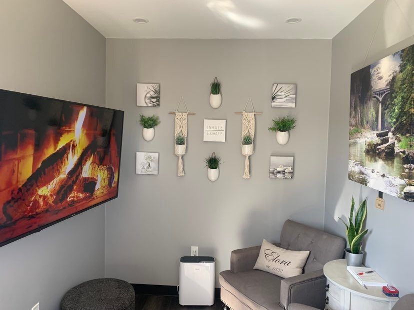 Cozy gray room with fireplace screen, art wall, armchair, and potted plants.