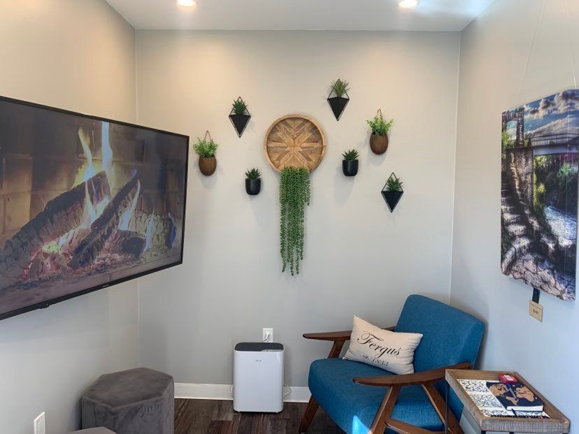 Cozy room with a TV, blue chair, wall decor, and an air purifier.