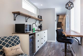 Small kitchen area with white cabinets, microwave, and dining area with a bar stool.