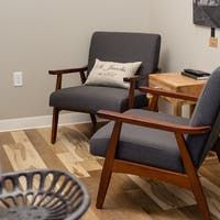 Two gray armchairs with wooden frames, wooden flooring.