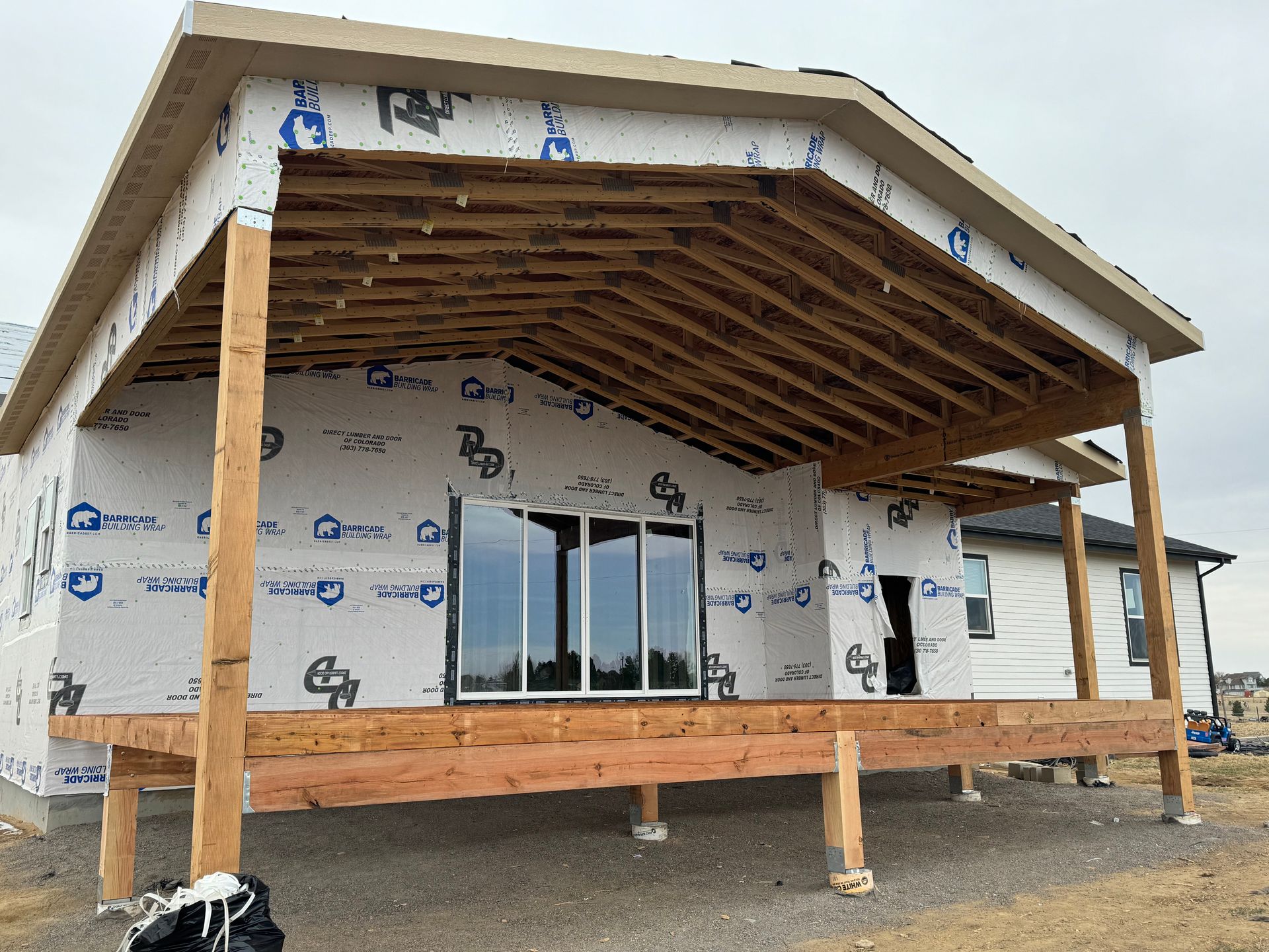 A house is being built with a large porch and a lot of windows.