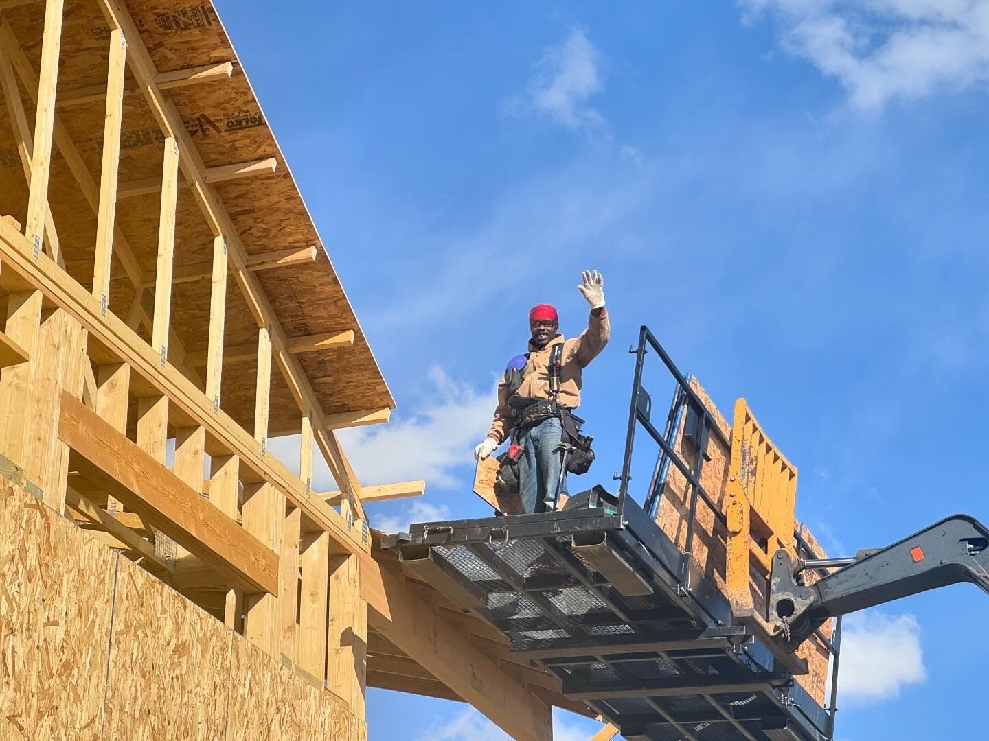 A construction worker is standing on top of a crane.