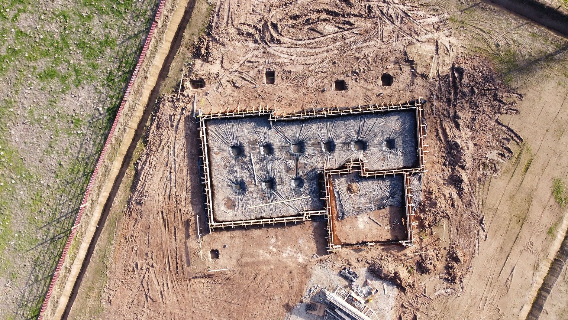 An aerial view of a building under construction in a dirt field.