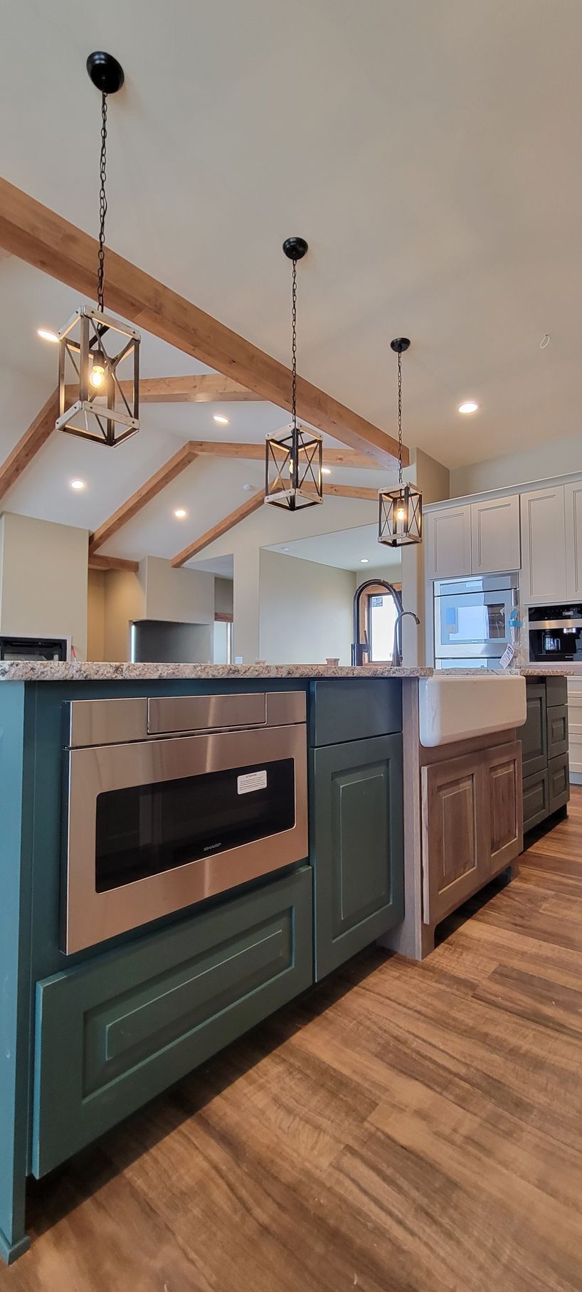 A kitchen with green cabinets , stainless steel appliances , a sink and a microwave oven.