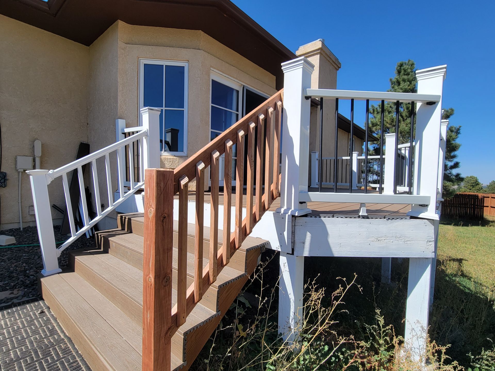 A deck with stairs and a white railing in front of a house.