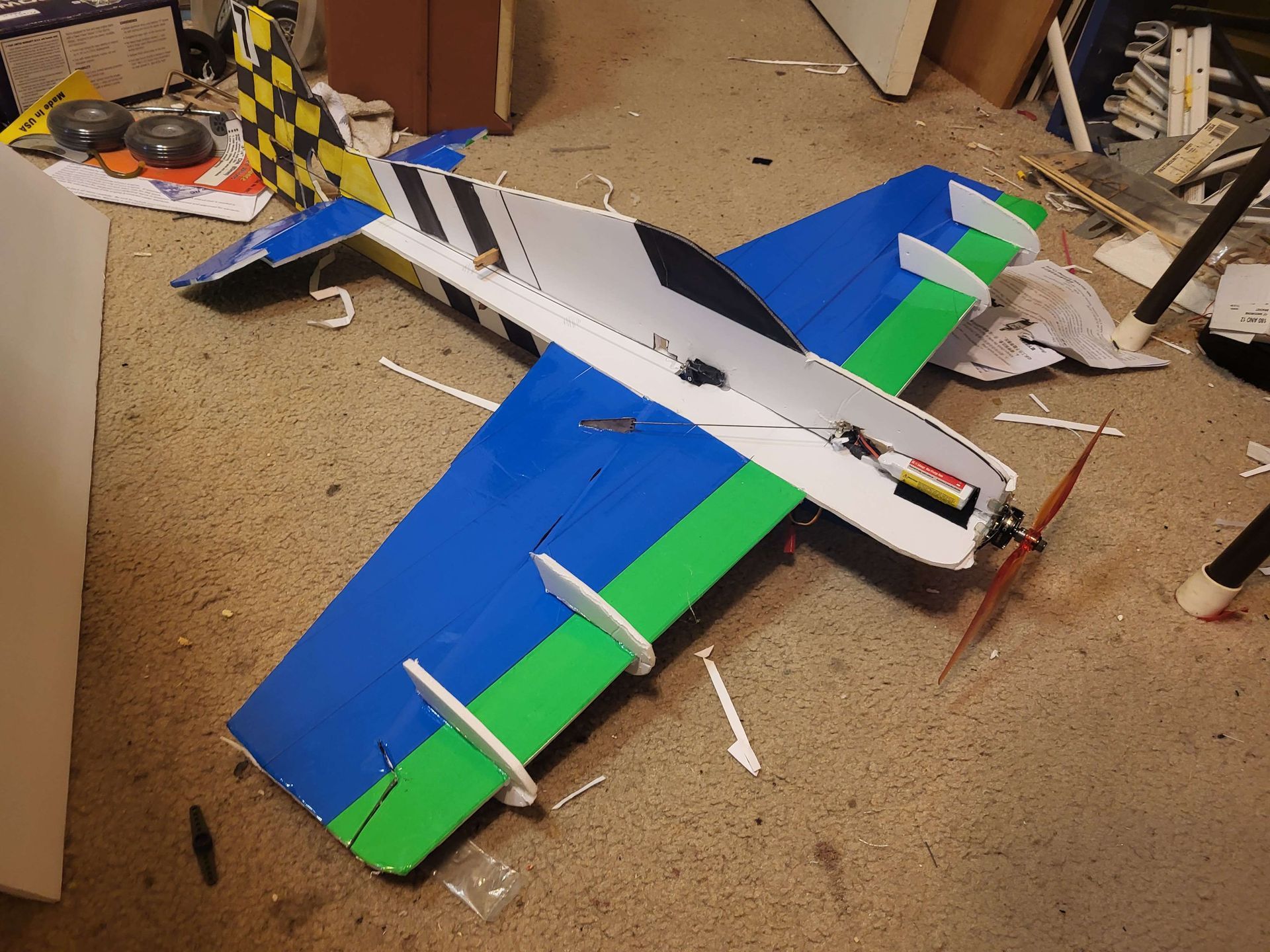 A blue and green model airplane is laying on the floor