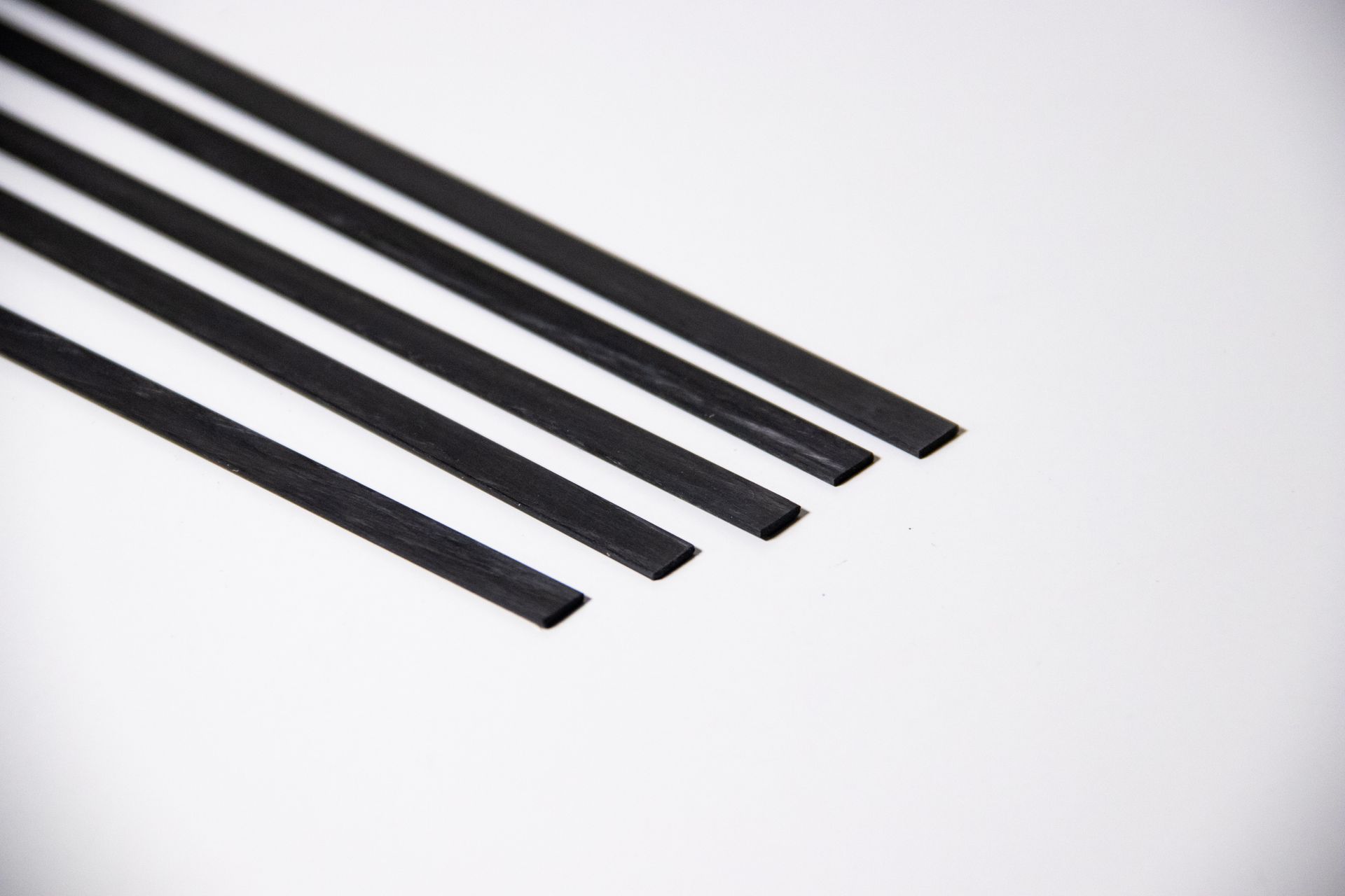 A close up of a row of black sticks on a white surface.