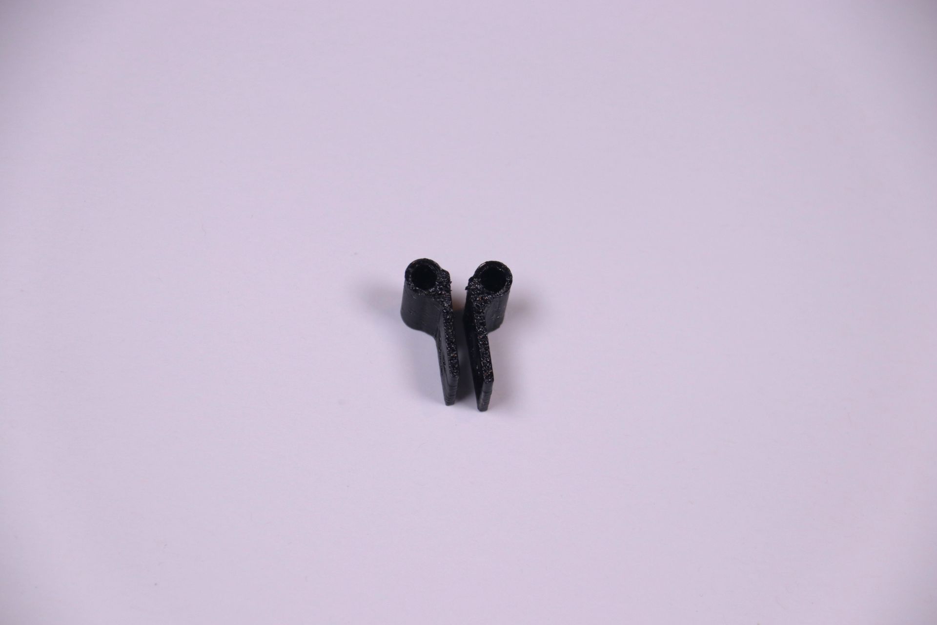 Two small black plastic clips on a light purple background