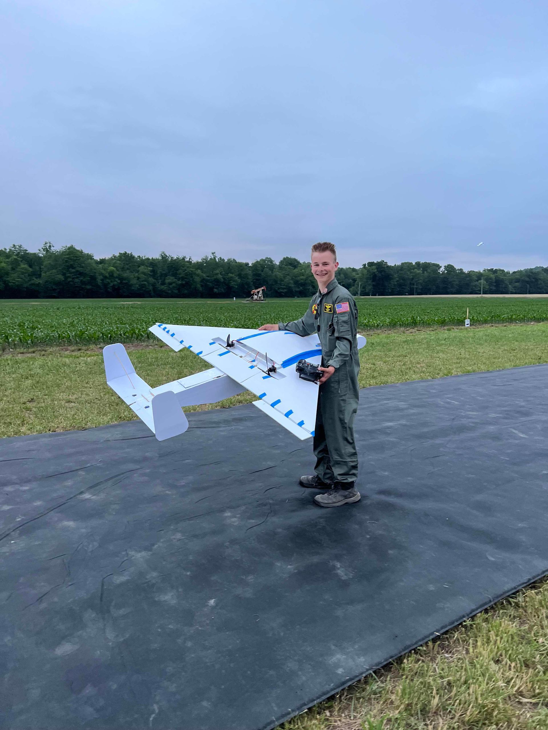 A man is standing on a runway holding a model airplane.