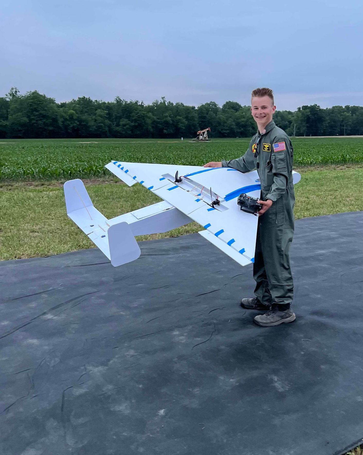 A man in a military uniform is holding a model airplane on a runway.