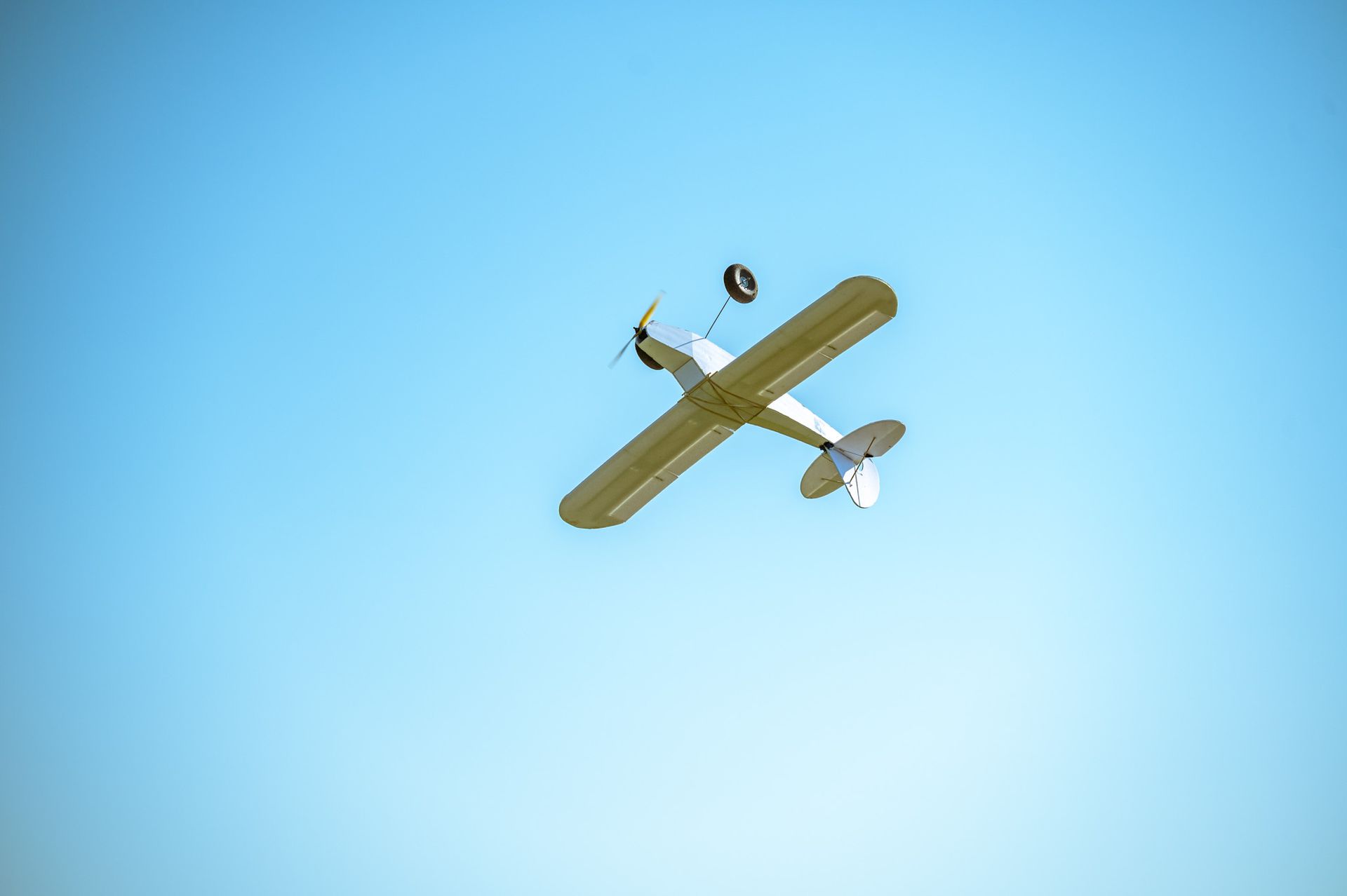 A small plane is flying through a clear blue sky.