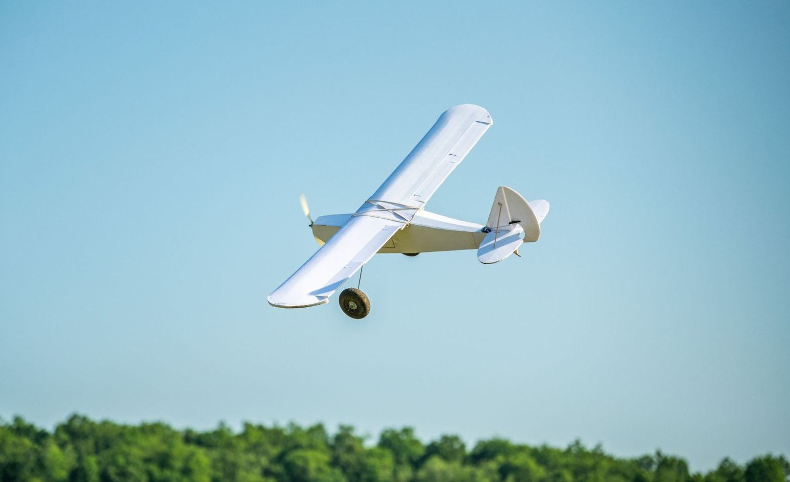 A small plane is flying in the sky over a field.